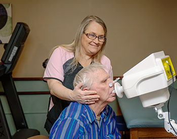 CCMH Patient Roy Myers breathes into an oscillometer while Kim Robleado, Pulmonary Rehabilitation Specialist at CCMH, assists by supporting his cheeks.photo of nurse holding man's cheeks while he breathes into an oscillometer machine